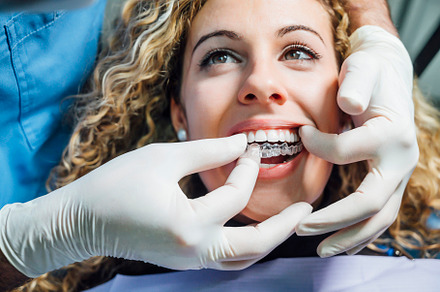 Doctor putting a clear dental aligne stock photo containing woman and girl, a Health & Medical Photo by karrastock