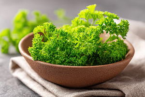 Fresh parsley bunches arranged in a rustic clay bowl on a textile surface, a Food & Drink Photo by AlyaAnd