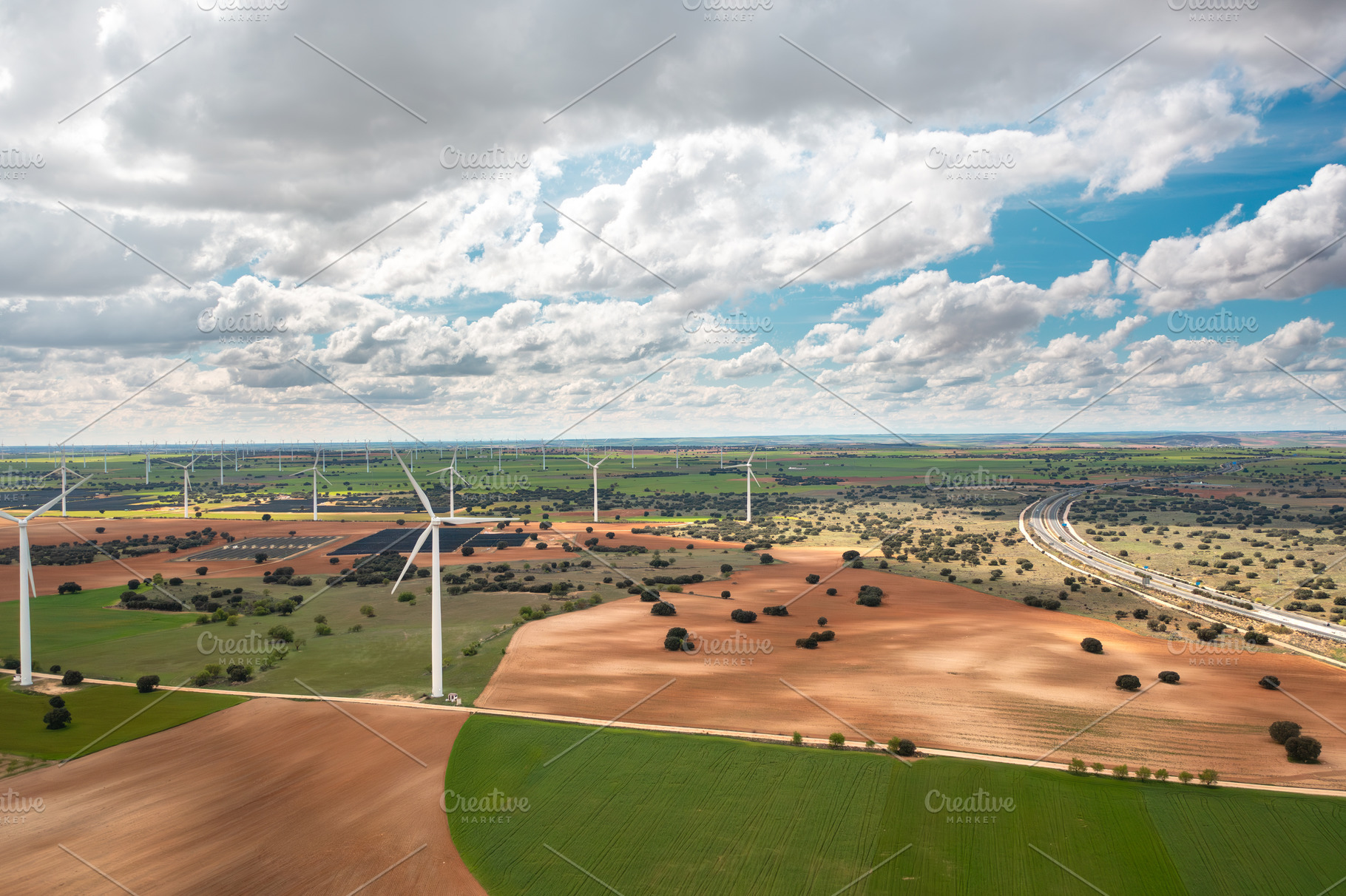 Wind turbines spinning across open countryside under cloudy sky, a Photo by andreonegin market