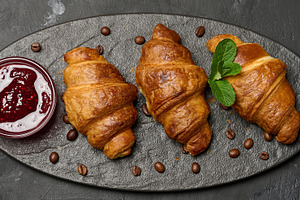 Golden croissants lined up on a dark stone board with raspberry, a Food & Drink Photo by ndanko