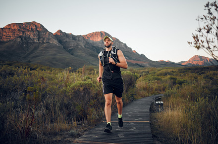 Runner, fitness on mountains and man running in nature for outdoor workout, wellness and healthy lifestyle with energy, goals and motivation. Sports person exercise or training run on hiking road, a Photo by Peopleimages.com