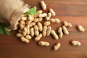 Cloth sack filled with peanuts scattered on rustic wooden table, a Food & Drink Photo by Davizro's Market
