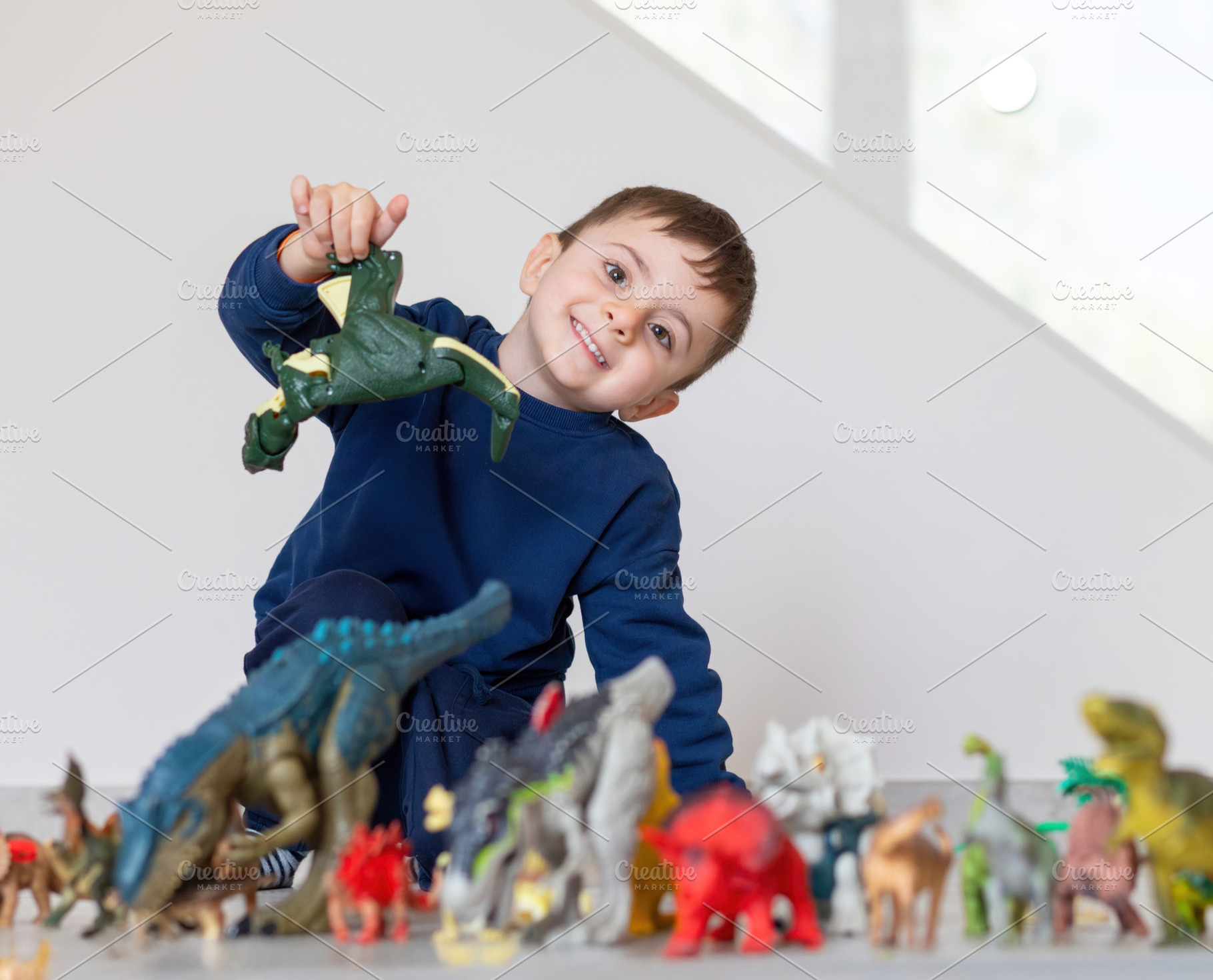 Happy child playing with dinosaur toys at home, a Person Photo by Antonio Gravante Market