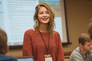Young woman smiling at conference pr, a Photo by Pixeness Studio