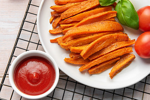 Sweet potato fries with ketchup and fresh basil, a Food & Drink Photo by Olena Rudo