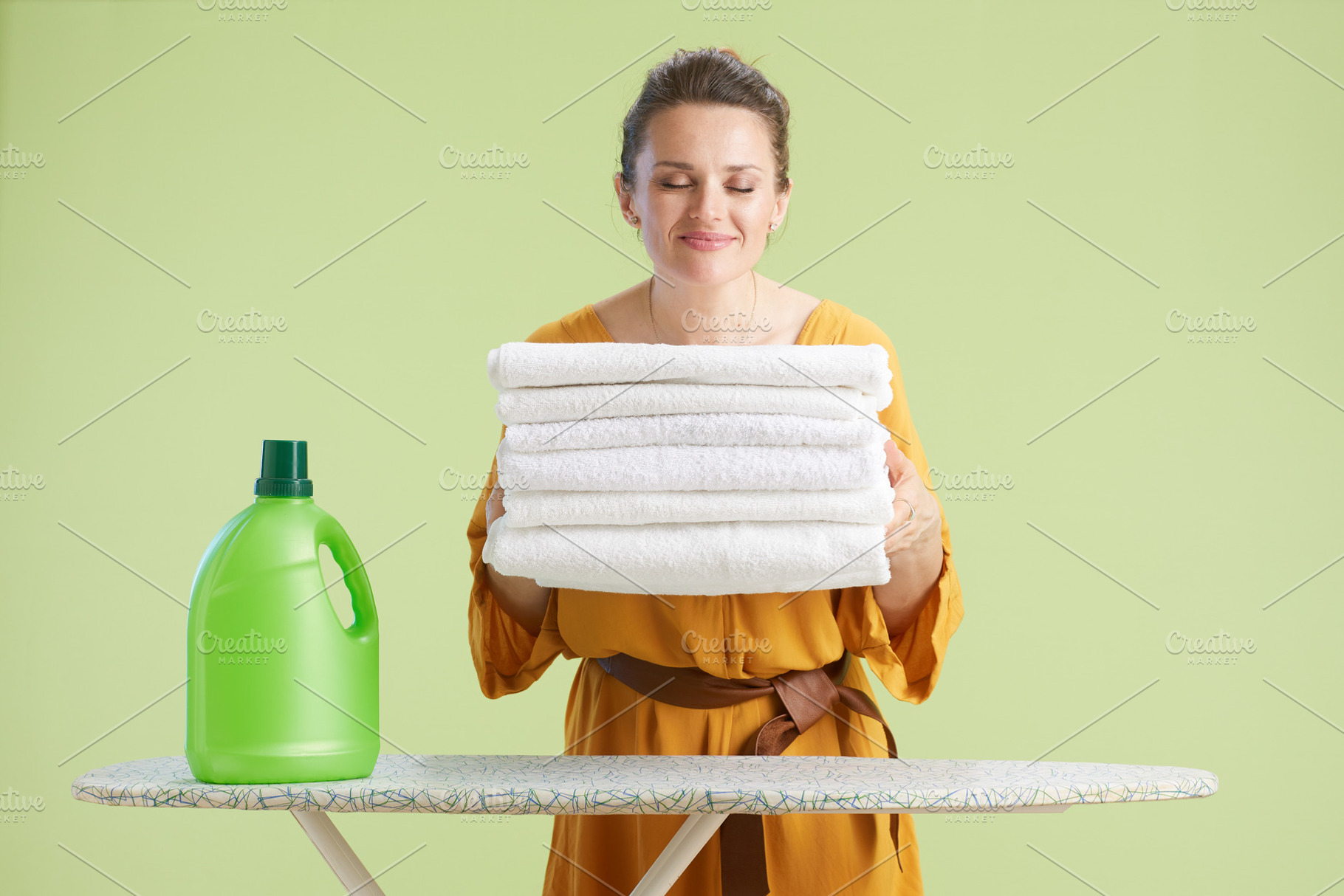 Content woman holding fresh towels near detergent, a Person Photo by Alliance Images