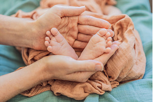 Newborn tiny feet surrounded by, a Person Photo by Elizaveta Galitskaya