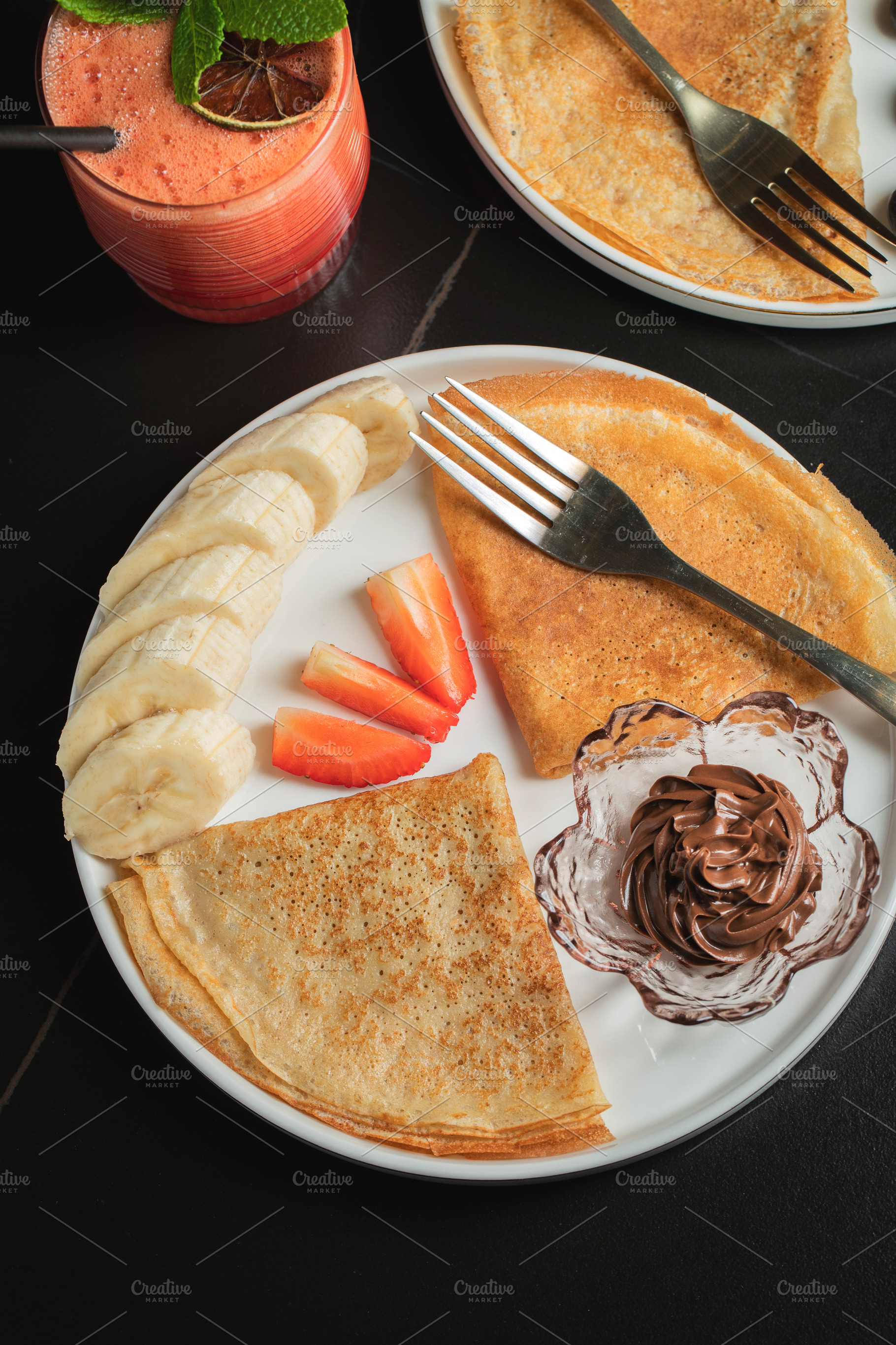 A plate of crepes filled with chocolate spread and topped with banana slices an, a Food & Drink Photo by Budarinphoto