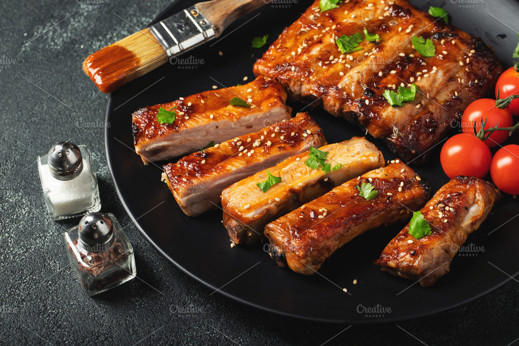 Hot grilled spare ribs from a summer BBQ served on a plate with sauce. Top view, a Food & Drink Photo by Budarinphoto