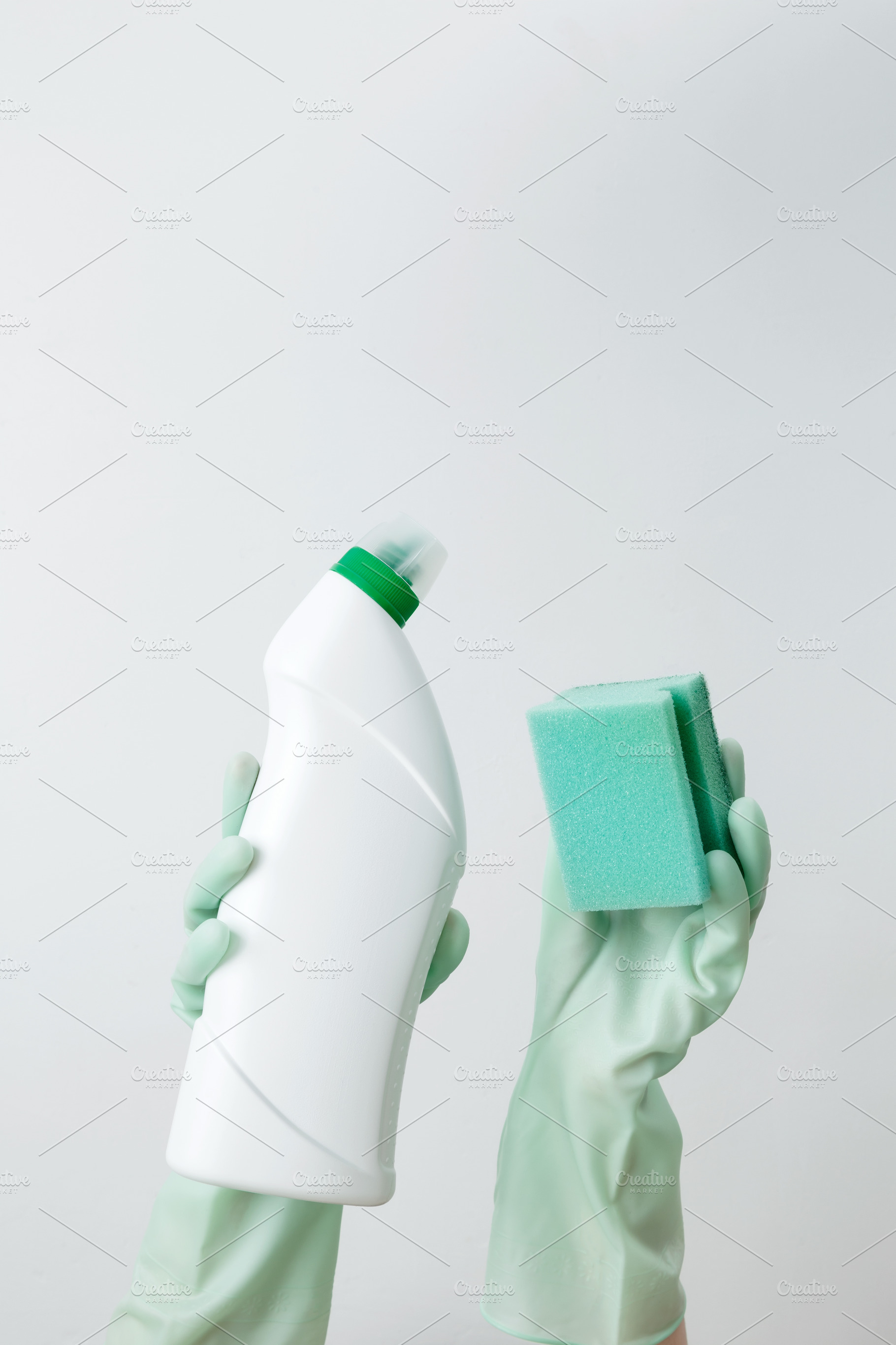 Woman wearing green rubber gloves holding cleaning detergent and sponge, ready, a Photo by matucha