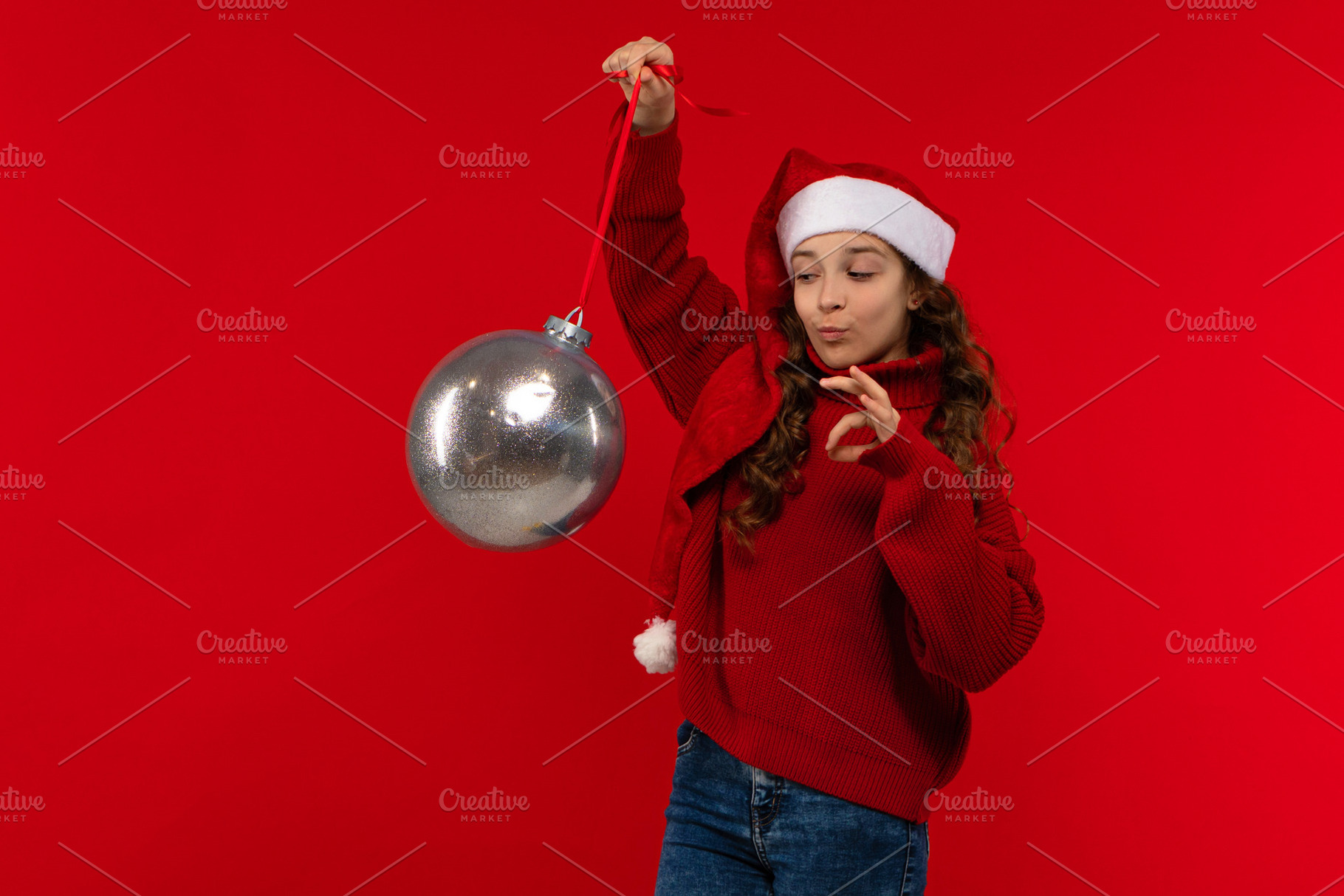 Girl in Santa hat and sweater holds, a Person Photo by Elena Vagengeim