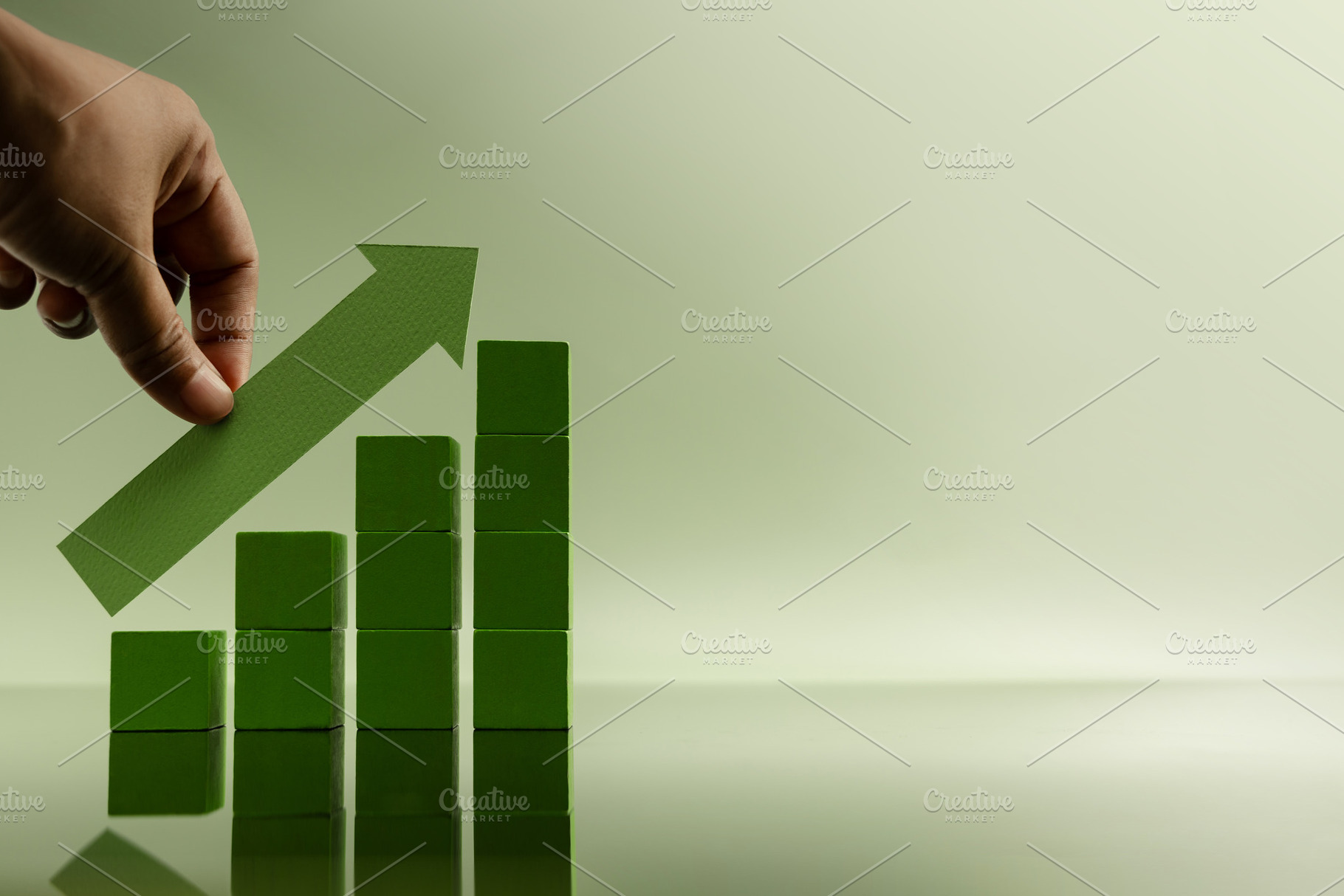 Hand placing green arrow on stacked bars, representing financial, a Photo by salmon.black