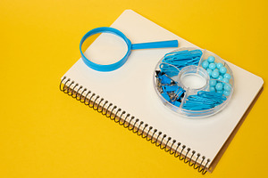 White notebook with blue magnifying glass and blue stationery in, a School & Education Photo by ndanko