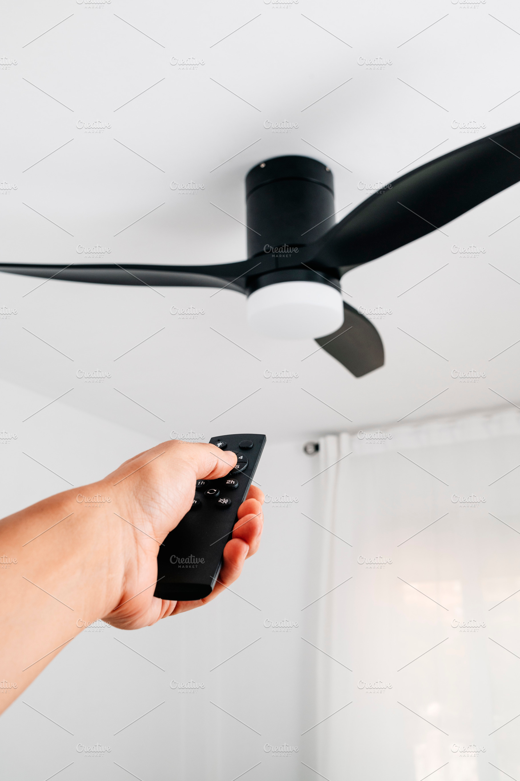ceiling fan controlled by a man using a remote, a Photo by Nito