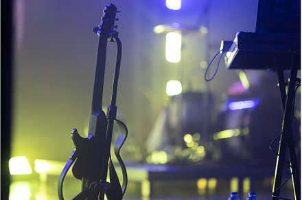 A guitar on a dimly lit stage., a Person Photo by Barcelona_dreams