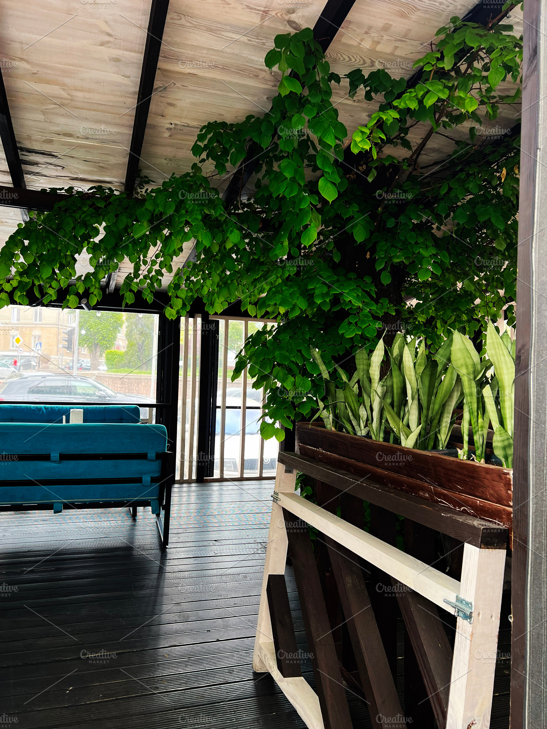 A cozy patio with green foliage and rustic wooden furniture., a Photo by AS photostudio