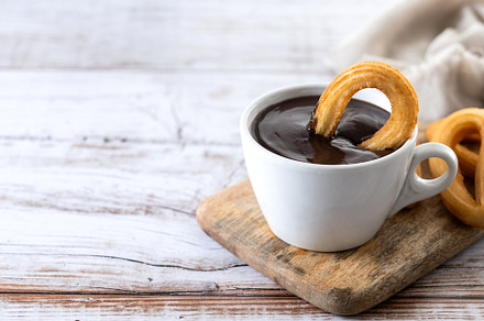 Traditional Spanish churros with hot chocolate breakfast on wooden table. Copy, a Food & Drink Photo by etorres69