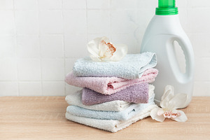 Stack of clean towels with laundry detergent bottle