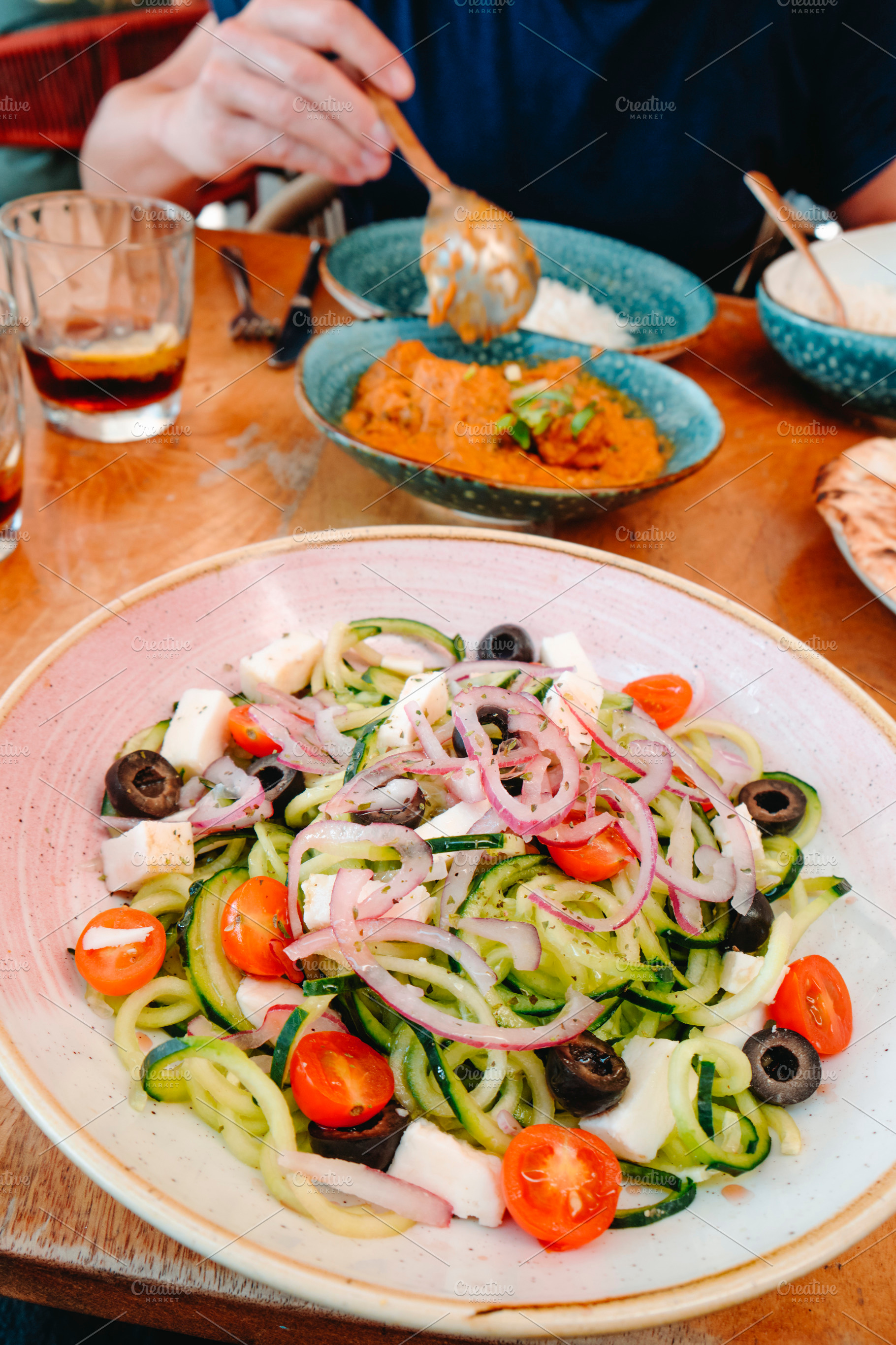 a bowl of spiralized cucumber salad on a table, a Photo by Nito