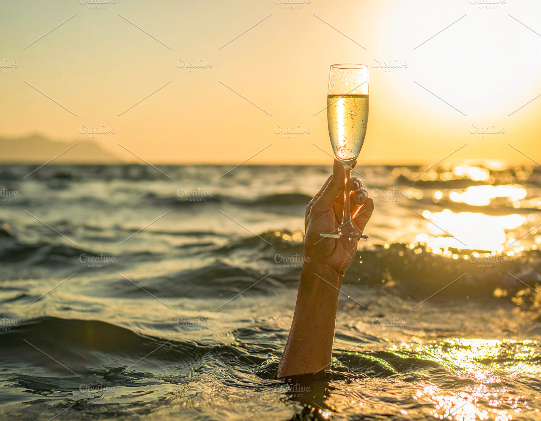 Arm raising a champagne glass from the middle of the sea, a Food & Drink Photo by DanFLCreativo