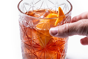 Hand reaching for an Old Fashioned cocktail in crystal glass, a Photo by etorres69