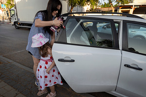 Mother preparing to put a bottle or sunscreen through the open b, a Person Photo by Imaginarium