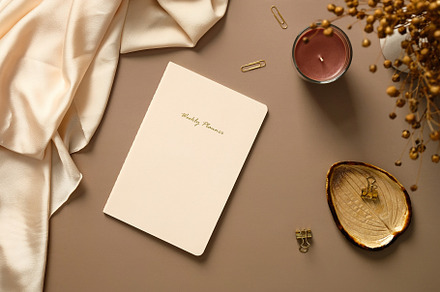 Weekly planner notebook, candle, office supplies, silk, dried flowers on brown, a Holiday Photo by photoguns