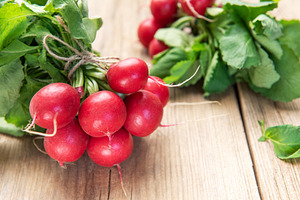 Fresh organic radishes with green leaves on rustic wood, a Food & Drink Photo by Olena Rudo