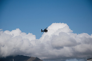 Helicopter flying above mountain with large clouds in Akranes, Iceland, a Photo by AS photostudio