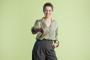 Confident green: A businesswoman's warm welcome, a Person Photo by Alliance Images
