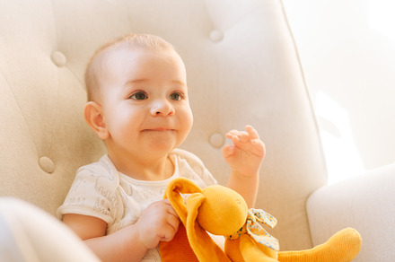 Portrait of a nine month old baby with a stuffed bunny sitting in a rocking cha