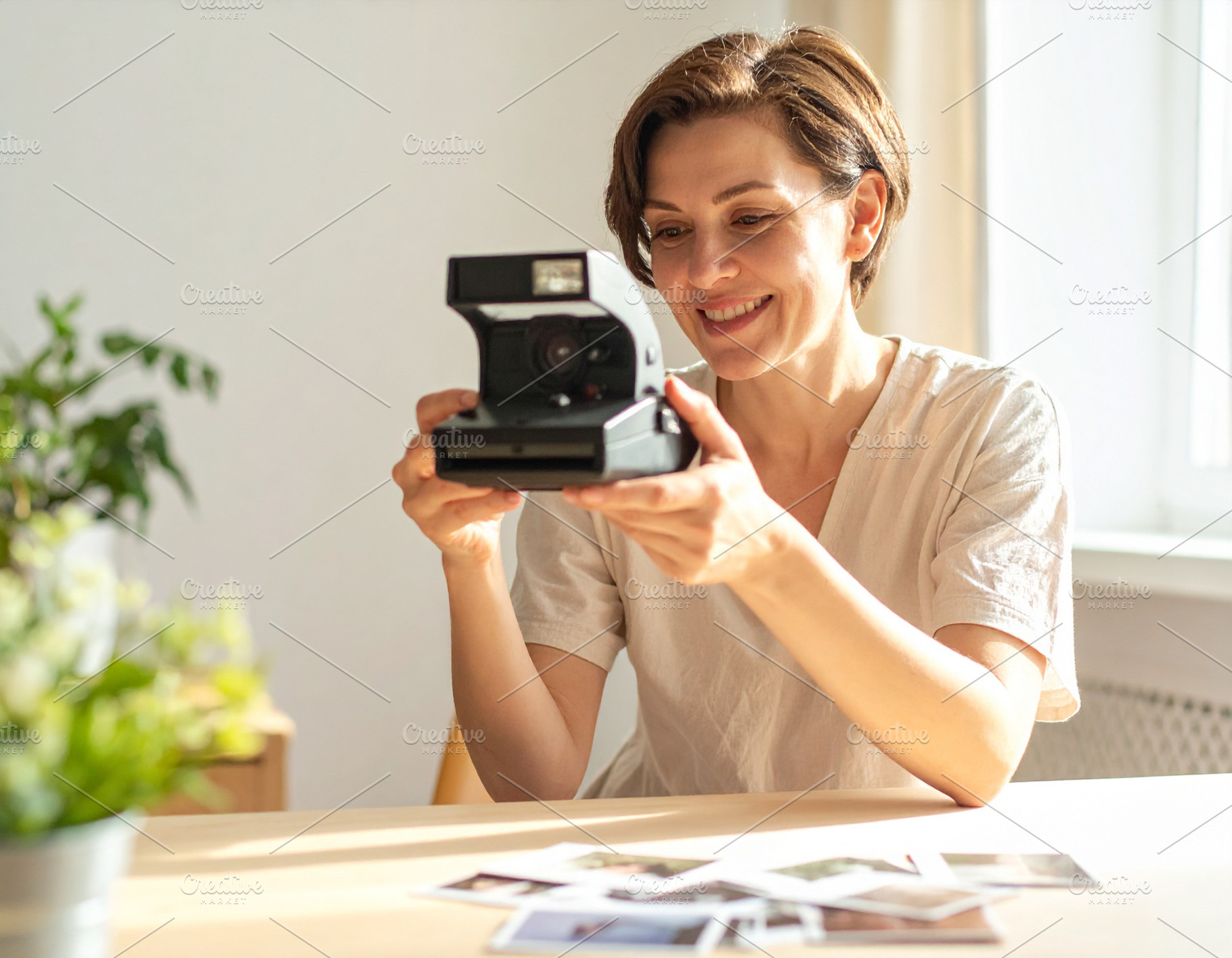 Woman holding analog camara while smiling at looking print photo, a Person Photo by DanFLCreativo