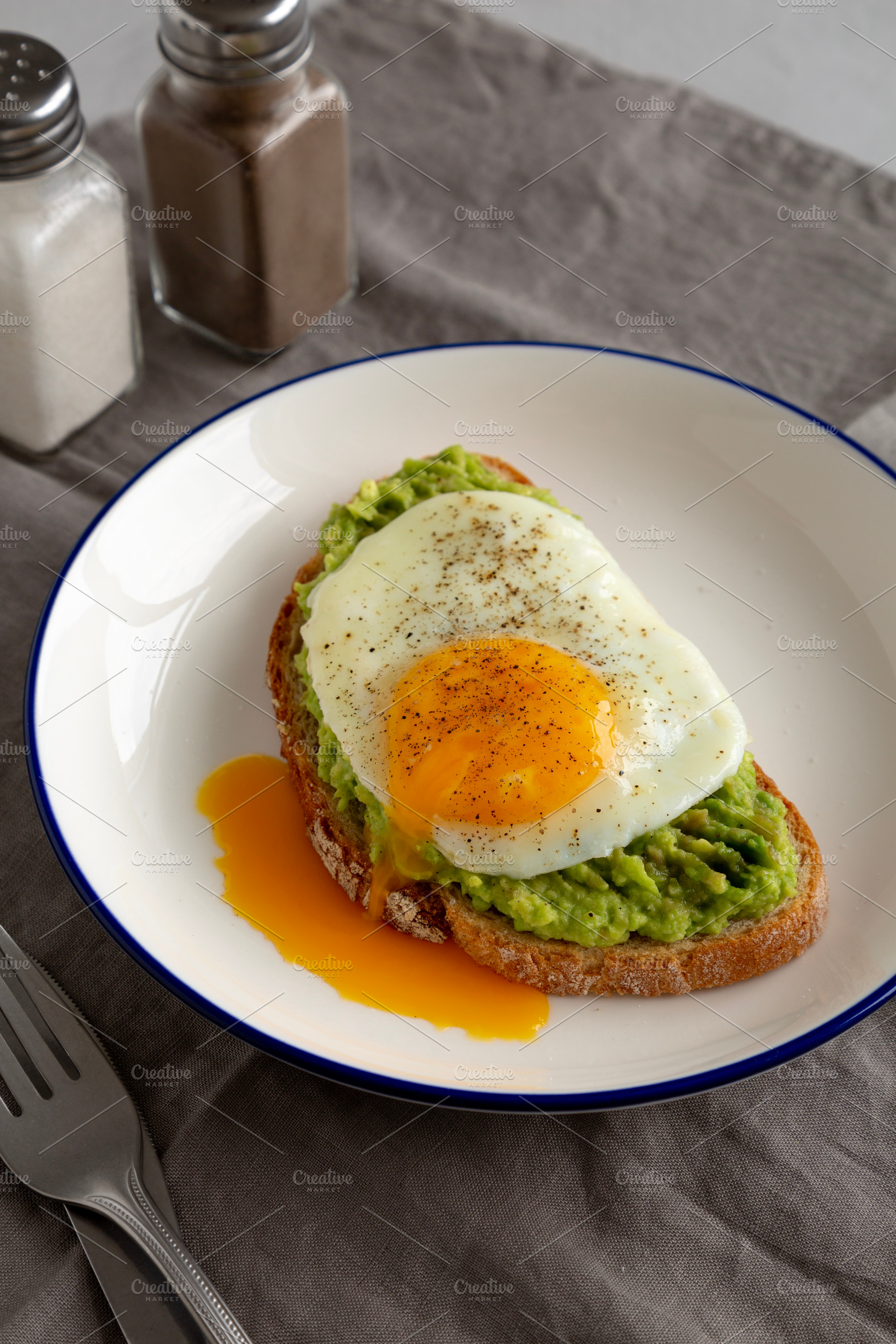 Homemade Avocado Toast with Egg on a Plate, side view. Close-up., a Food & Drink Photo by LiudmylaChuhunova