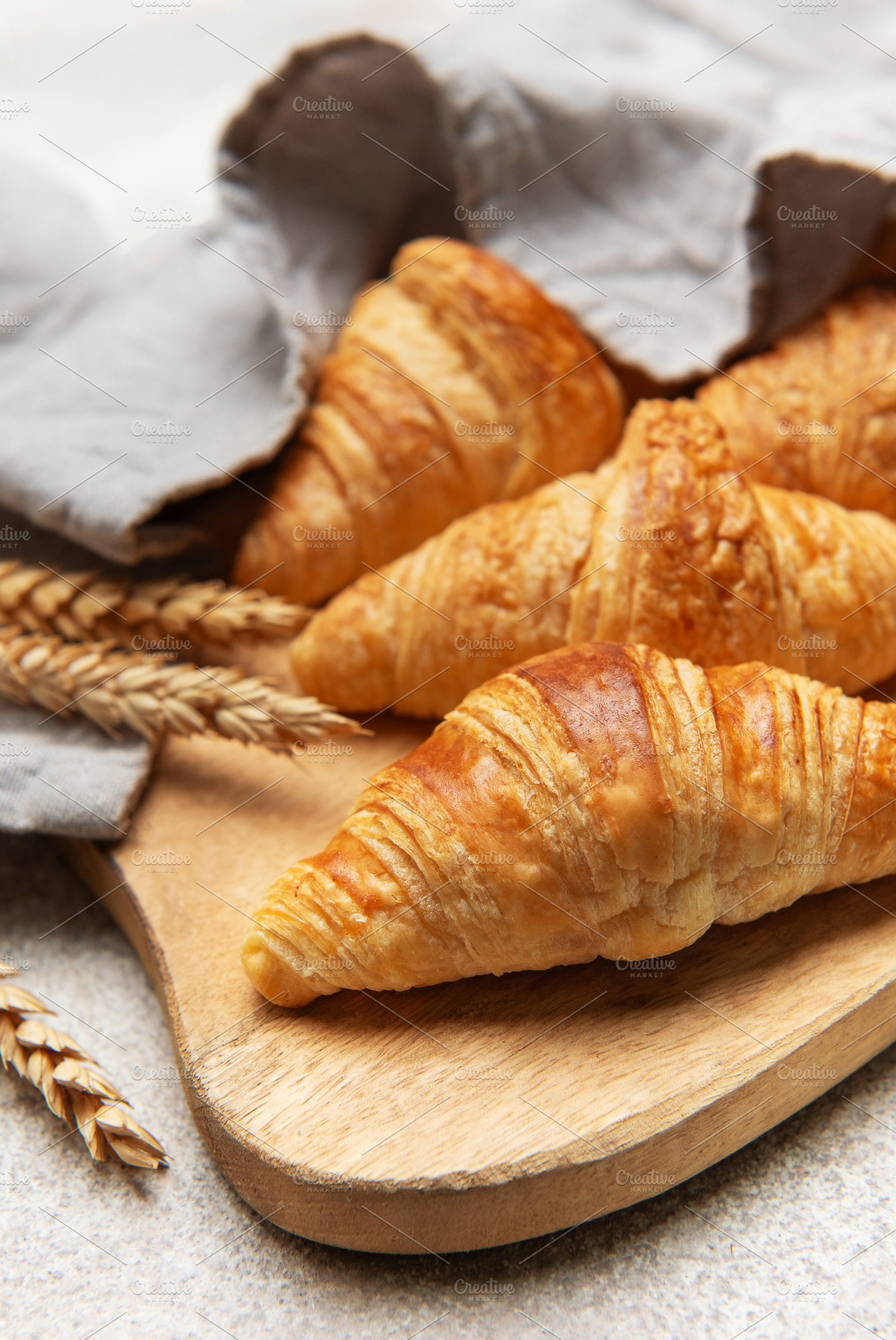 Freshly baked croissants resting on wooden cutting board with wh, a Food & Drink Photo by Olena Rudo