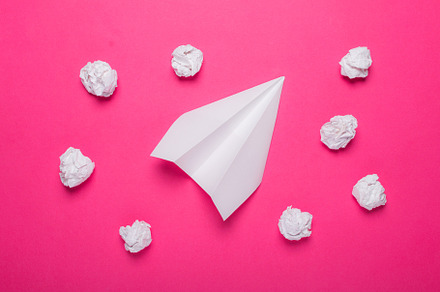 White paper plane and crumpled balls