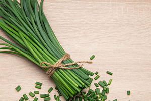 Freshly cut chives tied with twine on wooden table, a Photo by Olena Rudo