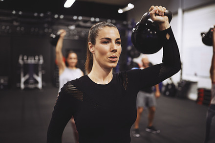 Young woman working out with weights in a gym class