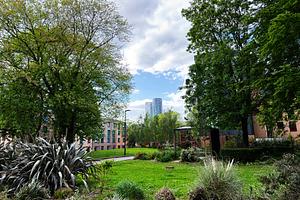 Urban park with trees and distant skyscraper in Manchester, UK r