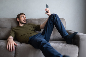 Man lying comfortably on a gray sofa