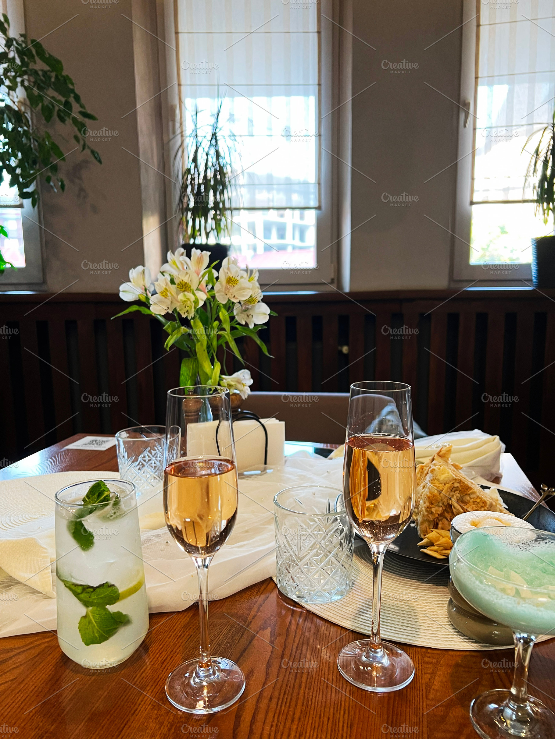 Elegant table setting with drinks, flowers, and light snacks in a cozy room, a Photo by AS photostudio