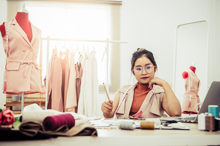 Attractive Asian female fashion designer working in home office, a Person Photo by Ministocker