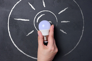 A human hand holding a light bulb, a chalk outline of the bulb w, a Business Photo by ndanko