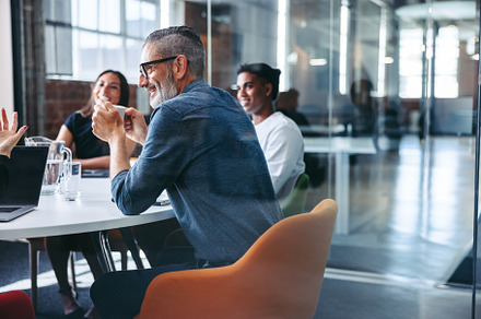 Happy mature businessman attending a meeting with his team, a Person Photo by Jacob Lund