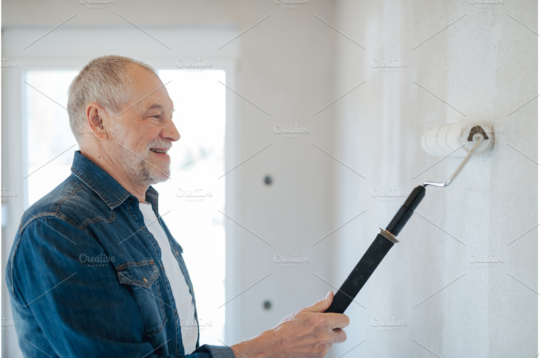 Senior man painting walls with, a Person Photo by HalfPoint