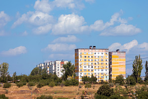 Colorful panel apartment blocks in a rural town with trees, dry, an Architecture Photo by Ales Munt