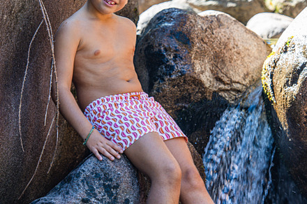Little boy on a waterfall of a river at summer