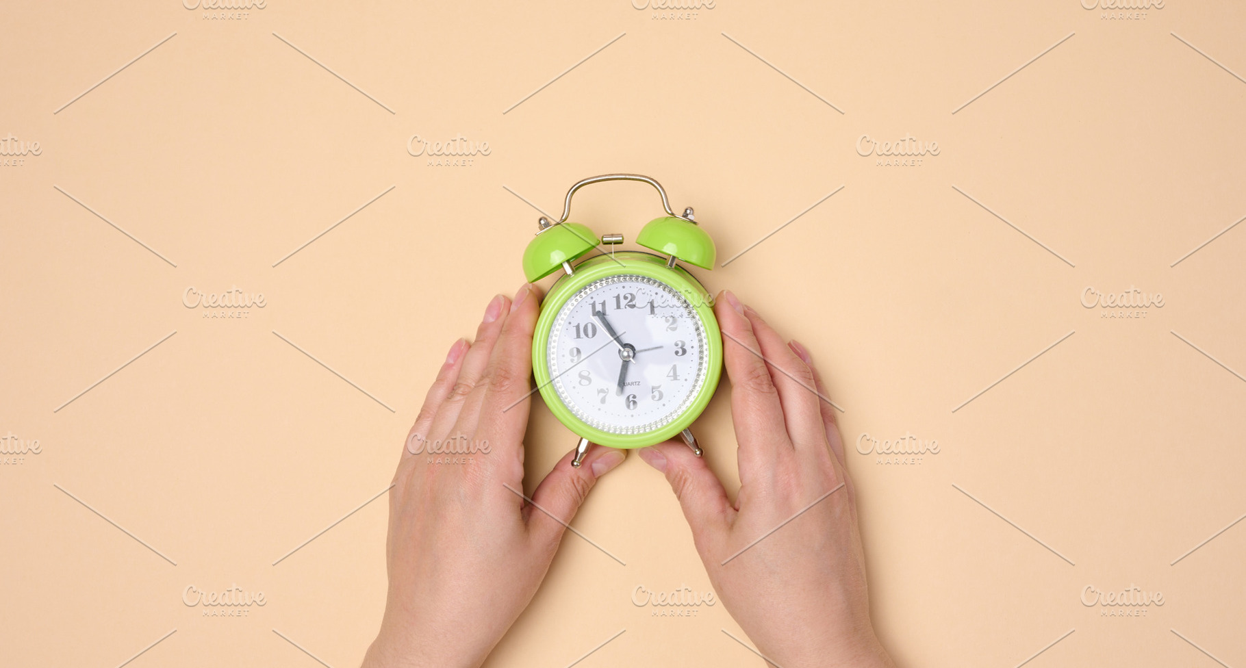 Hands holding green table alarm clock on neutral background., an Abstract Photo by ndanko
