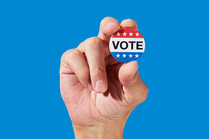 a man holds a vote badge between his fingers