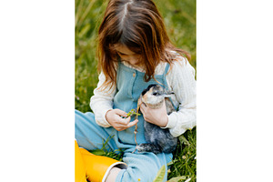 Young girl feeding pet bunny with, an Animal Photo by HalfPoint