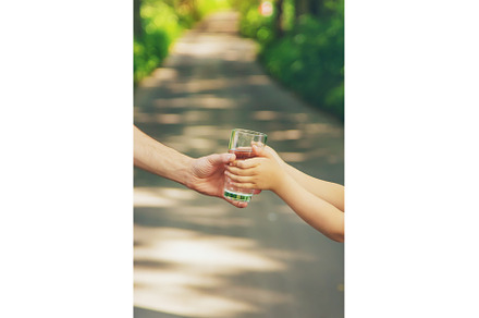 The father gives the child a glass, a Food & Drink Photo by yanadjana